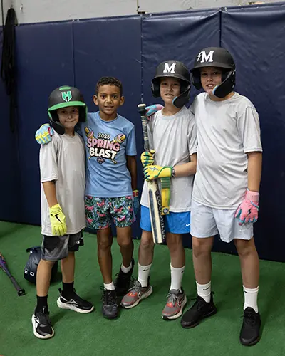 Birthday party guests in batting helmets inside the facility
